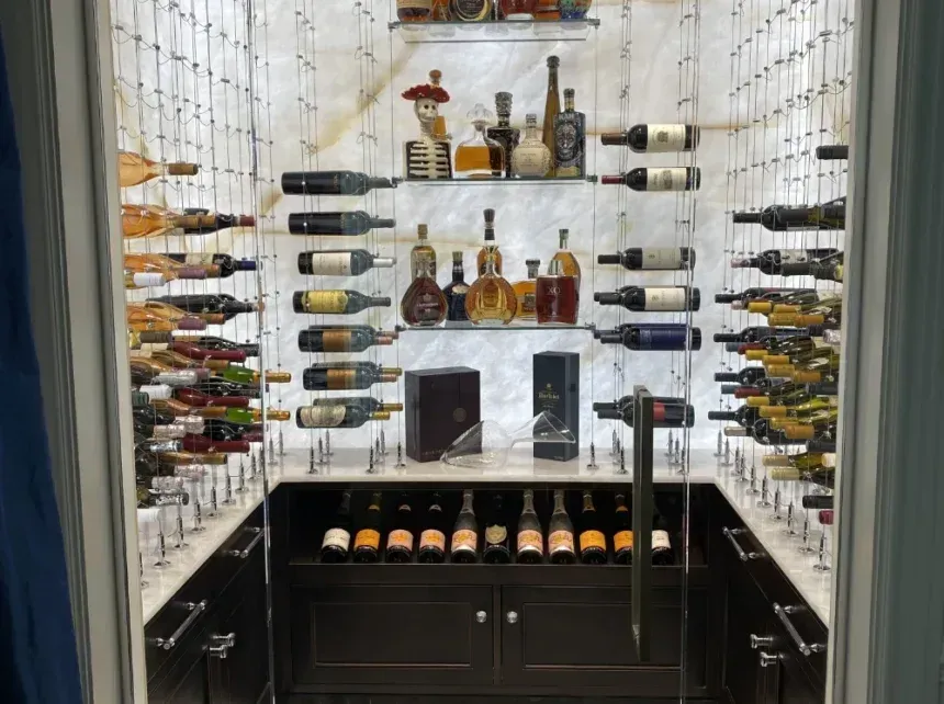 A modern, well-lit home wine cellar featuring bottle display racks on the walls, a display shelf, and lower cabinetry.