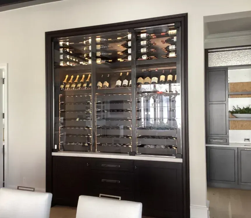 A large, dark wood built-in wine display cabinet with glass doors, shelves for wine bottles, and lower storage drawers.