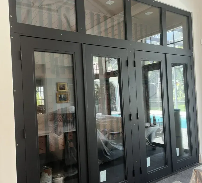 A wall of four black-framed glass patio doors with rectangular windows above, viewed from inside a light-colored room.