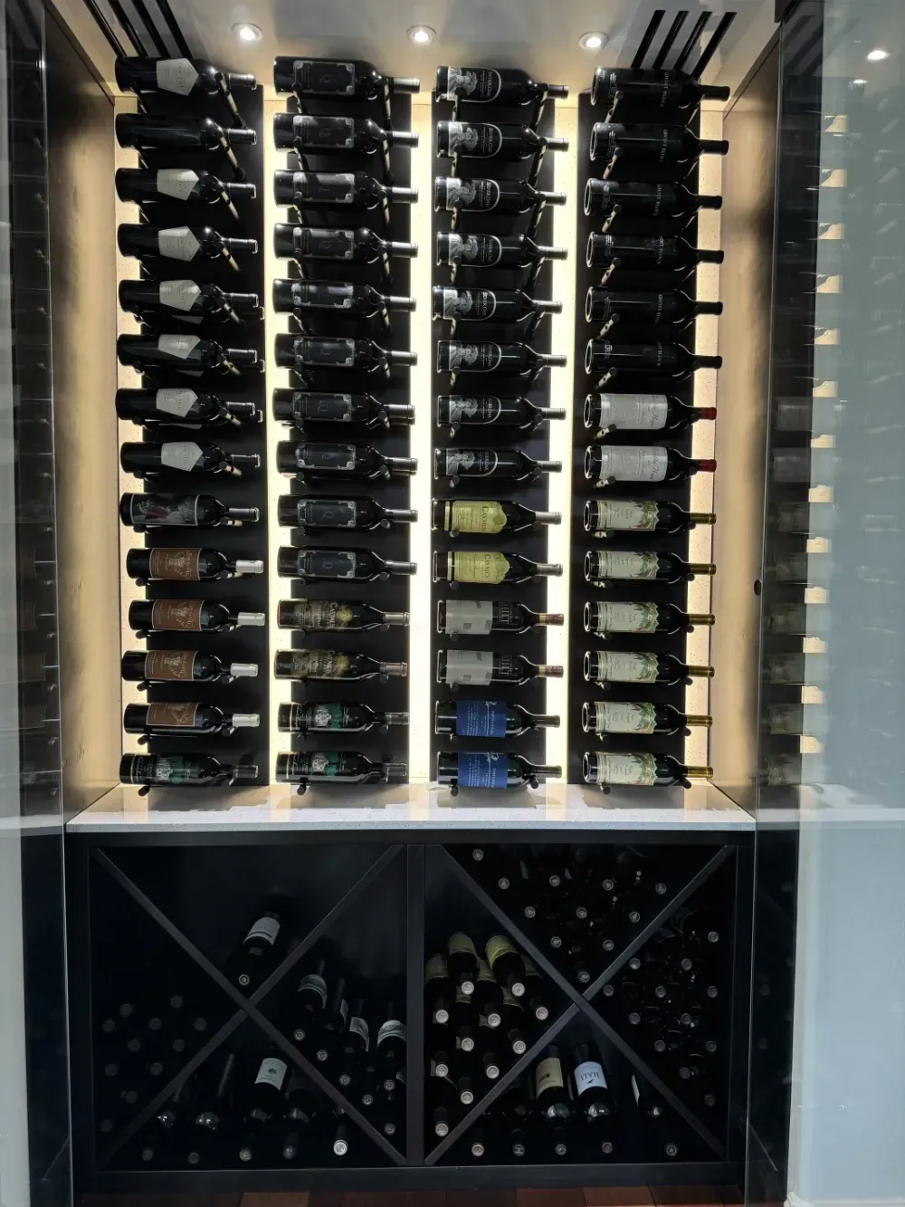 A modern wine rack with four vertical columns of individual bottle displays above diamond-shaped storage bins.