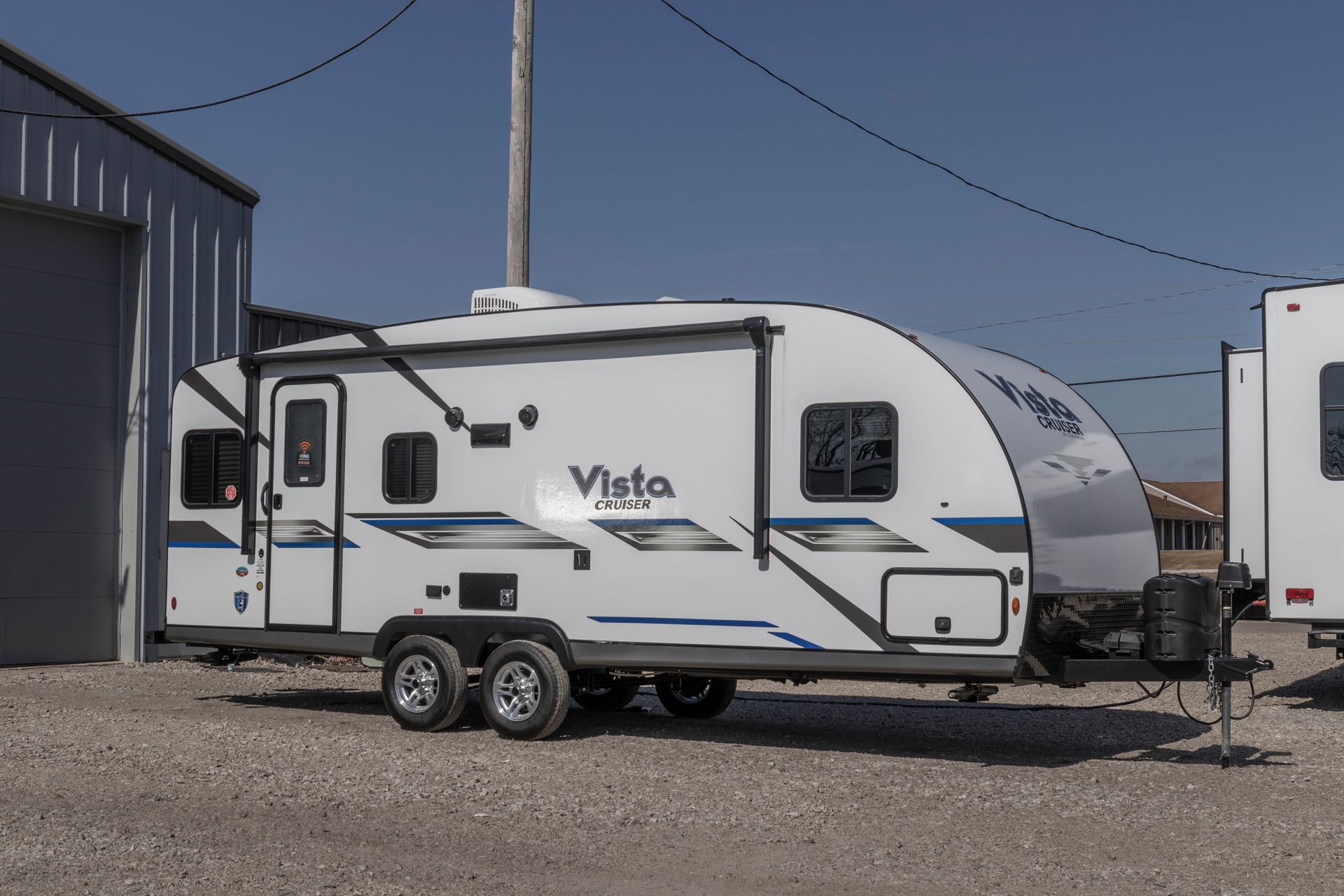 Un camping-car blanc est garé devant un garage.