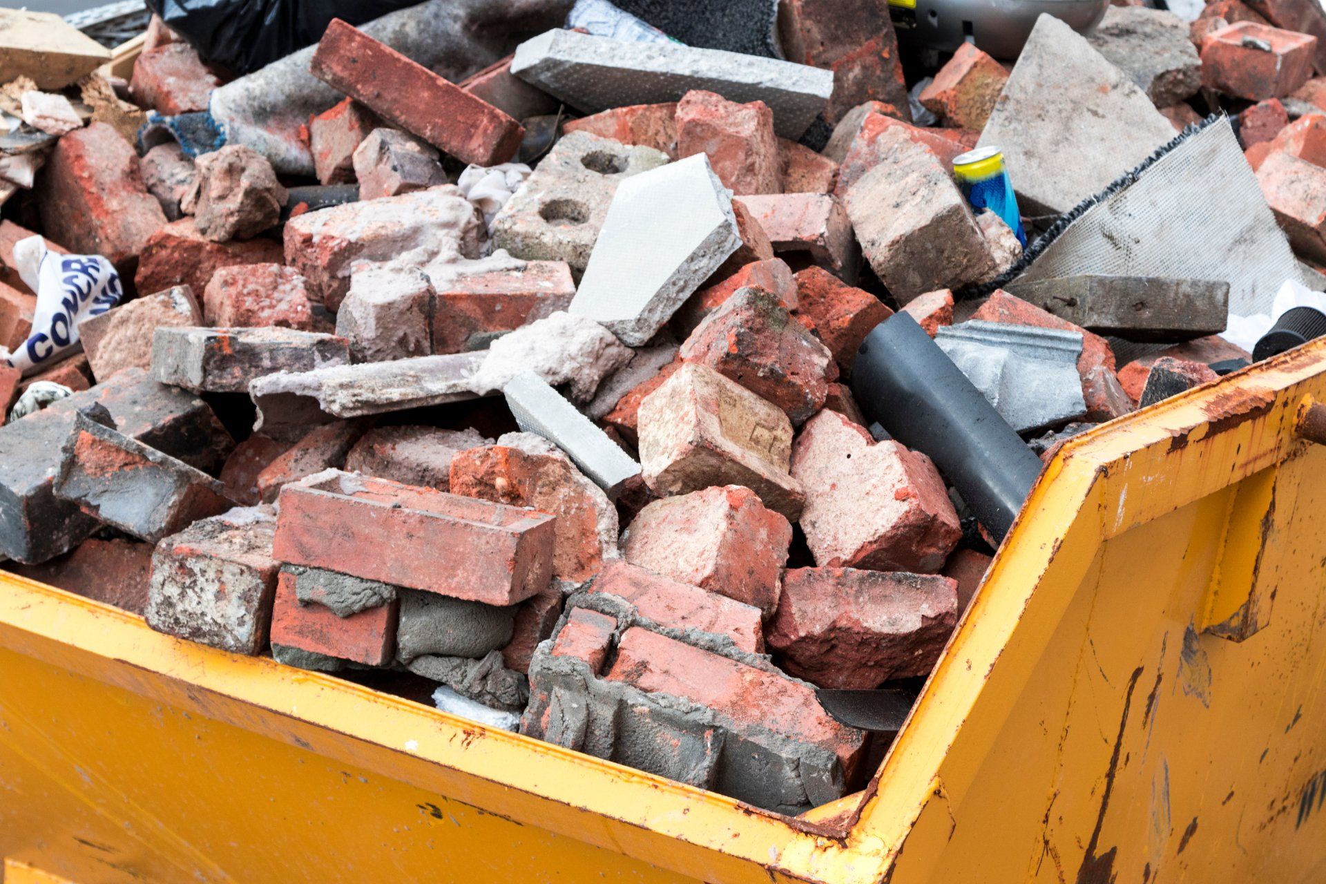 Yellow metal skip full of old bricks.