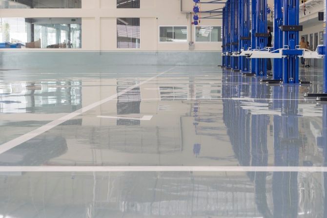 Empty polished industrial floor with blue machinery reflected on the surface in a bright workshop
