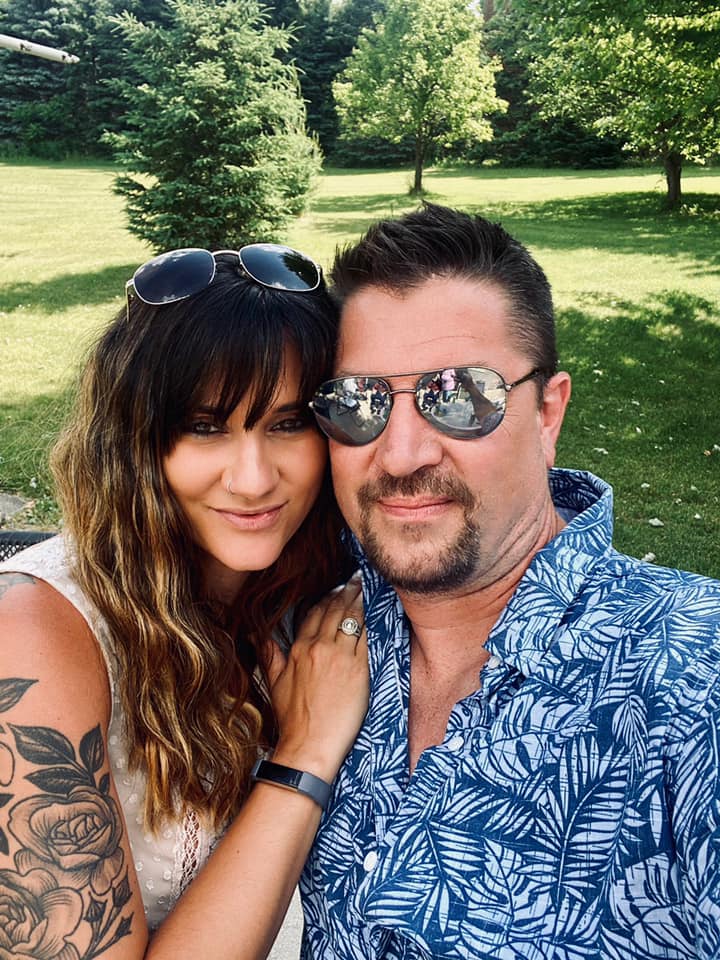 A man and a woman are posing for a picture in a park.