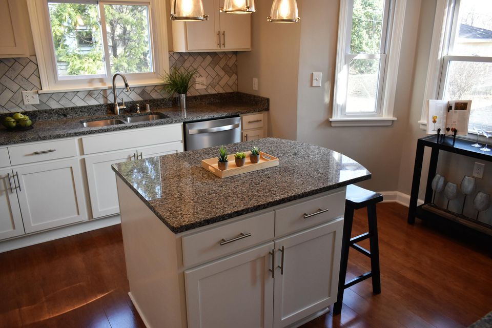 A kitchen with granite counter tops and white cabinets