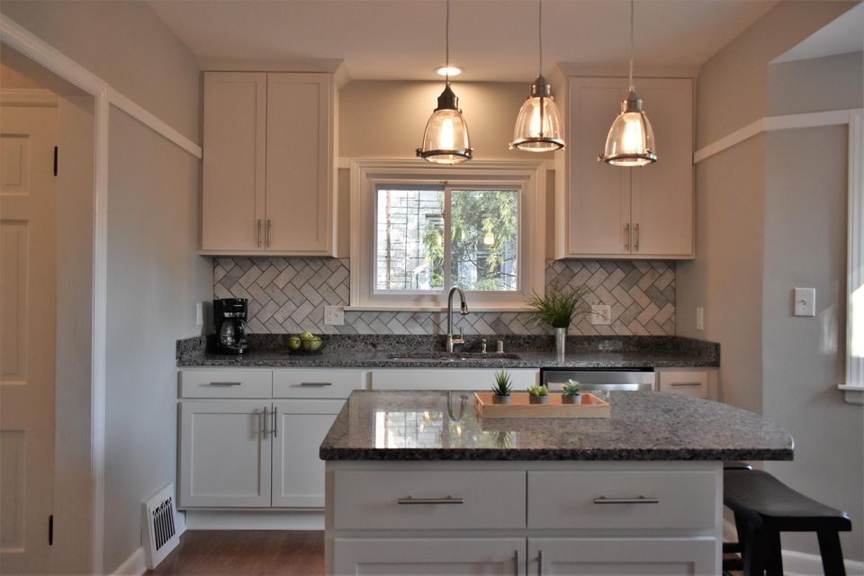 A kitchen with white cabinets and granite counter tops