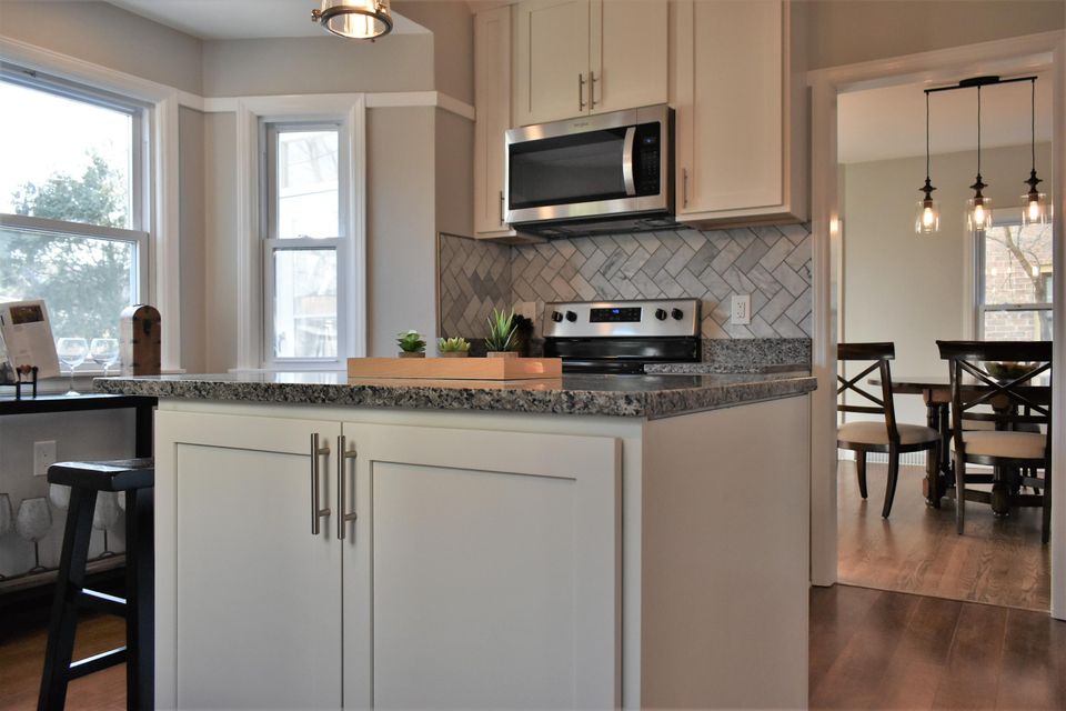 A kitchen with white cabinets , granite counter tops , stainless steel appliances and a large island.