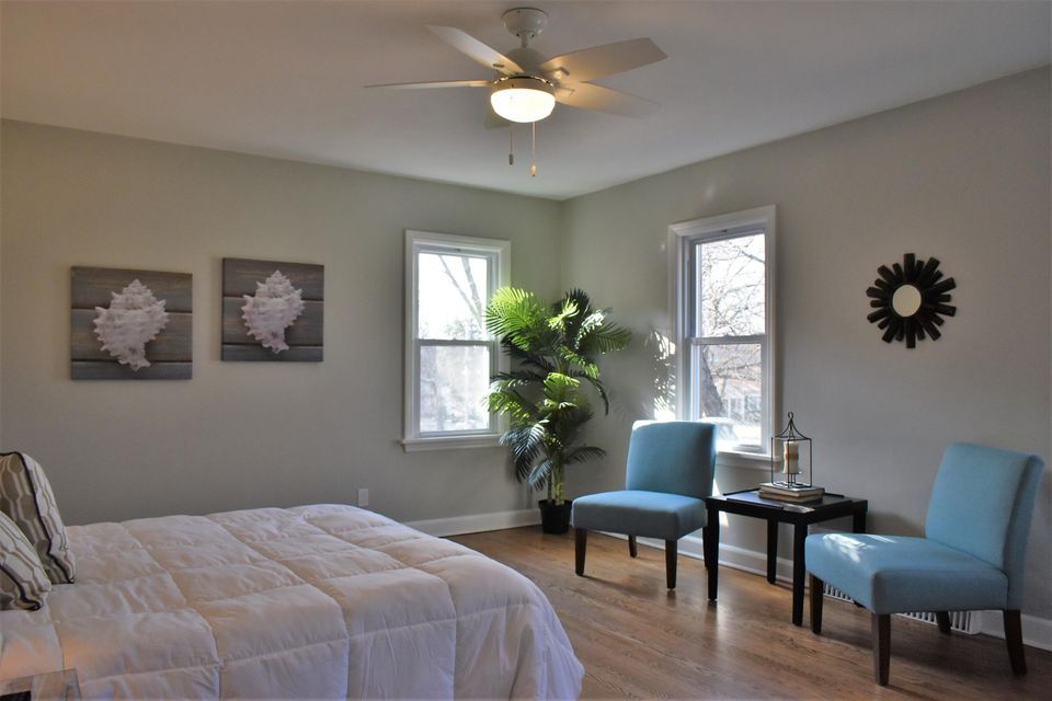 A bedroom with a bed , chairs and a ceiling fan