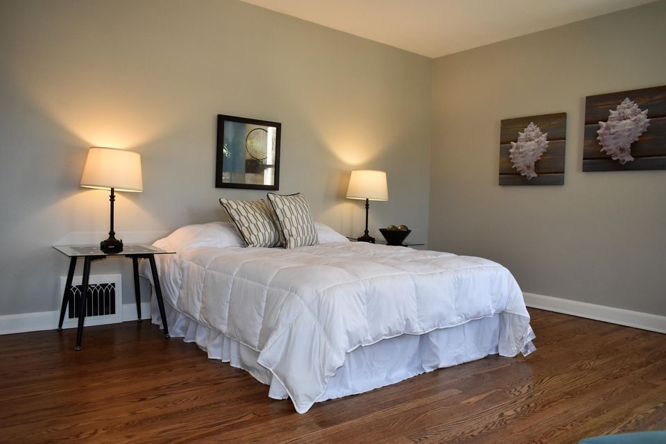 A bedroom with a bed , two lamps , a mirror and two paintings on the wall.