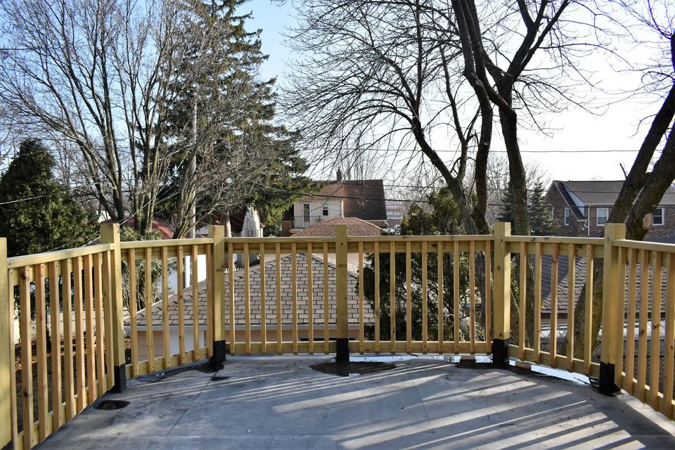 A wooden deck with a fence and trees in the background