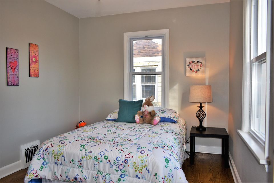 A bedroom with a bed , nightstand , lamp and window.