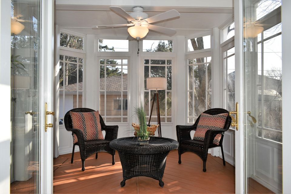 A sun room with wicker furniture and a ceiling fan