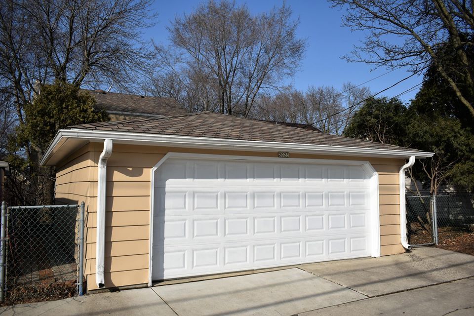 A garage with a white door and a chain link fence