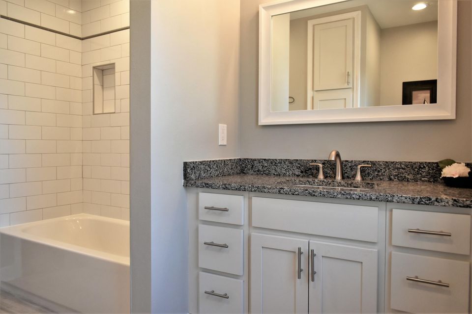 A bathroom with a sink , mirror and bathtub.