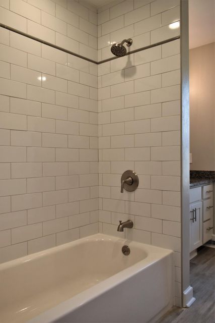 A bathtub in a bathroom next to a shower with white tiles.