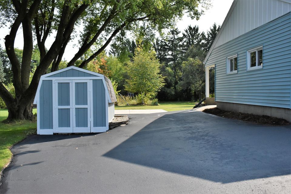 A shed in a driveway next to a house