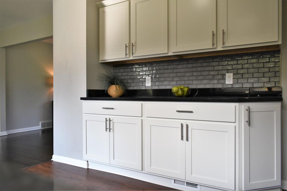 A kitchen with white cabinets and a black counter top.