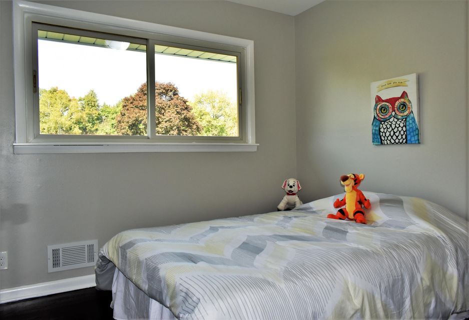A bedroom with a bed , a window and a painting of an owl on the wall.