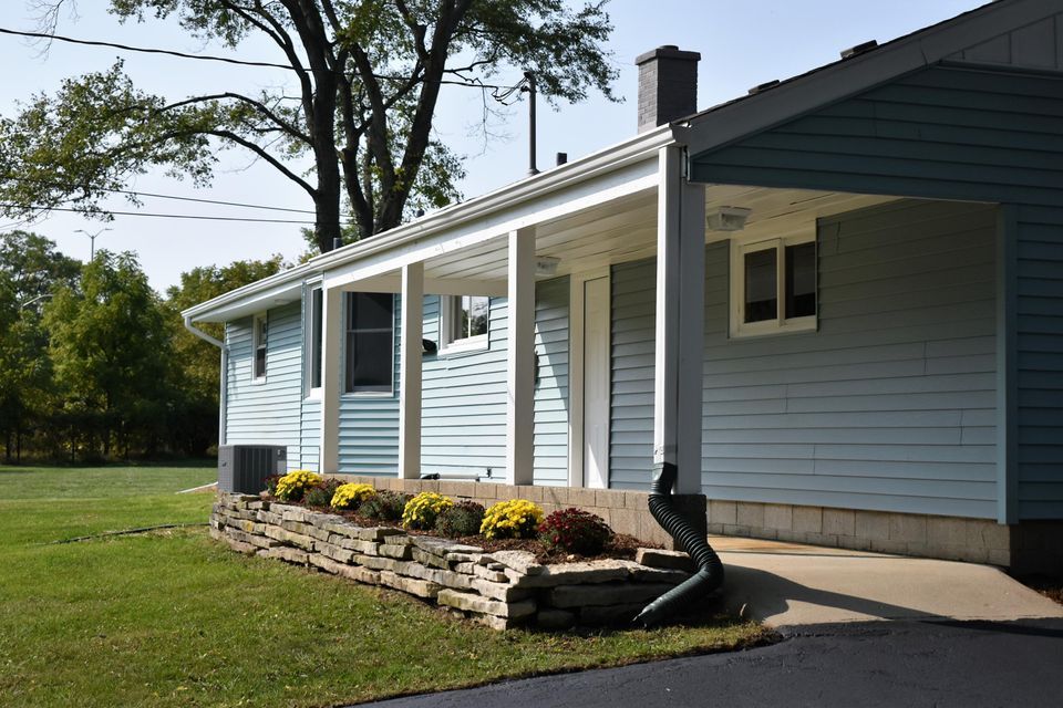 A blue house with a porch and a stone wall