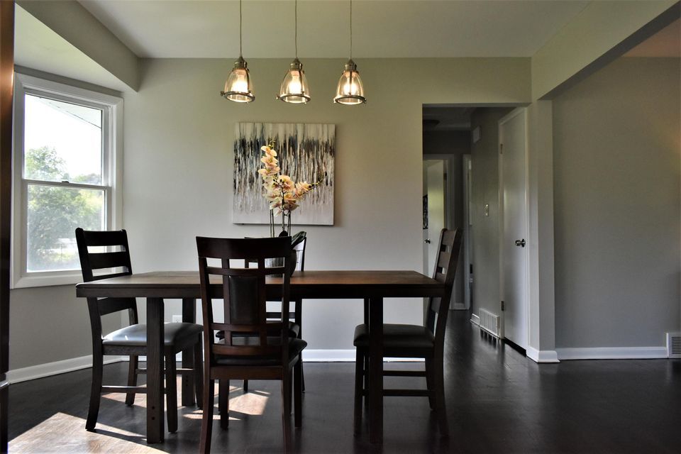 A dining room with a table and chairs and a painting on the wall