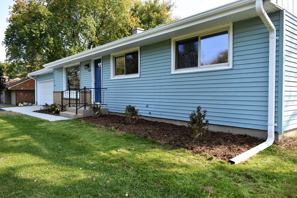 A blue house with a white gutter and a lawn in front of it.