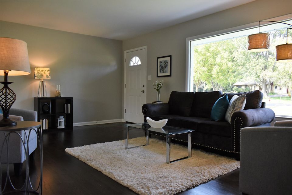 A living room with a black couch and a white rug