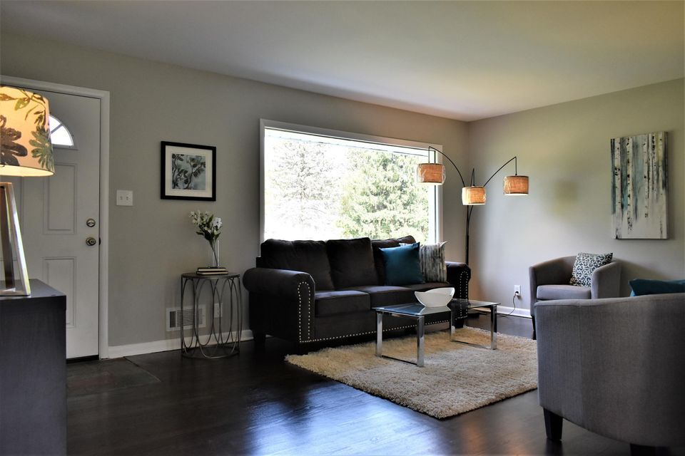 A living room with a couch , chairs , coffee table and rug.