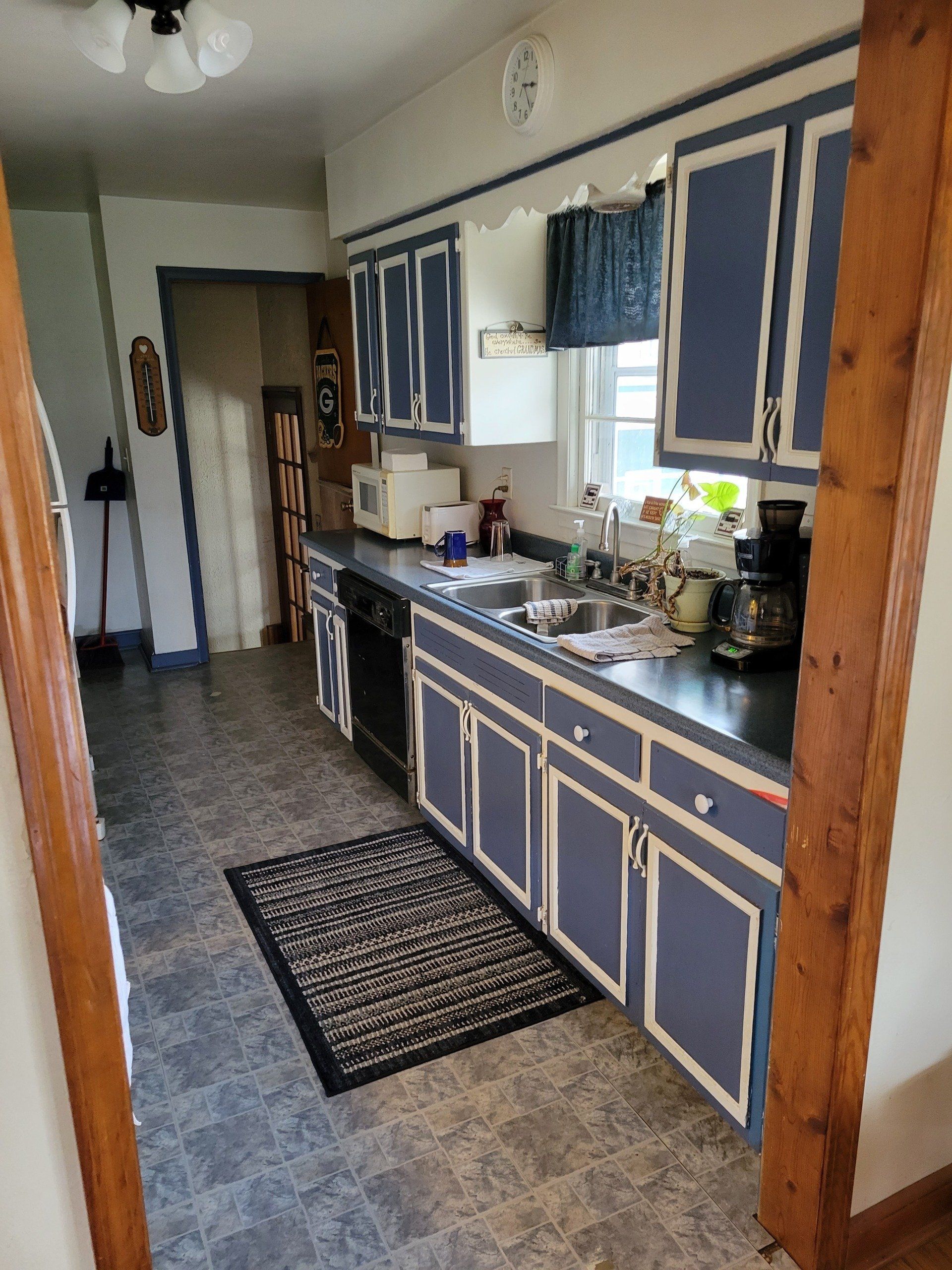 A kitchen with blue cabinets and a rug on the floor