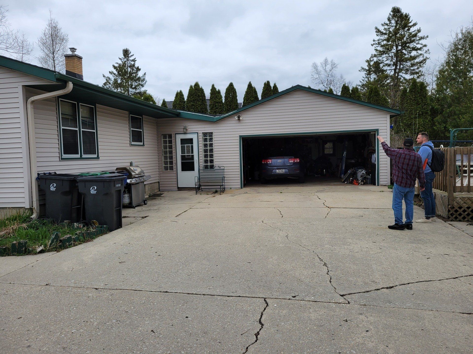 A man stands in front of a house with a car in the garage