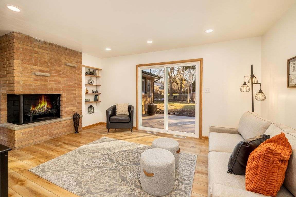 A living room with a couch, chair, fireplace and sliding glass doors.