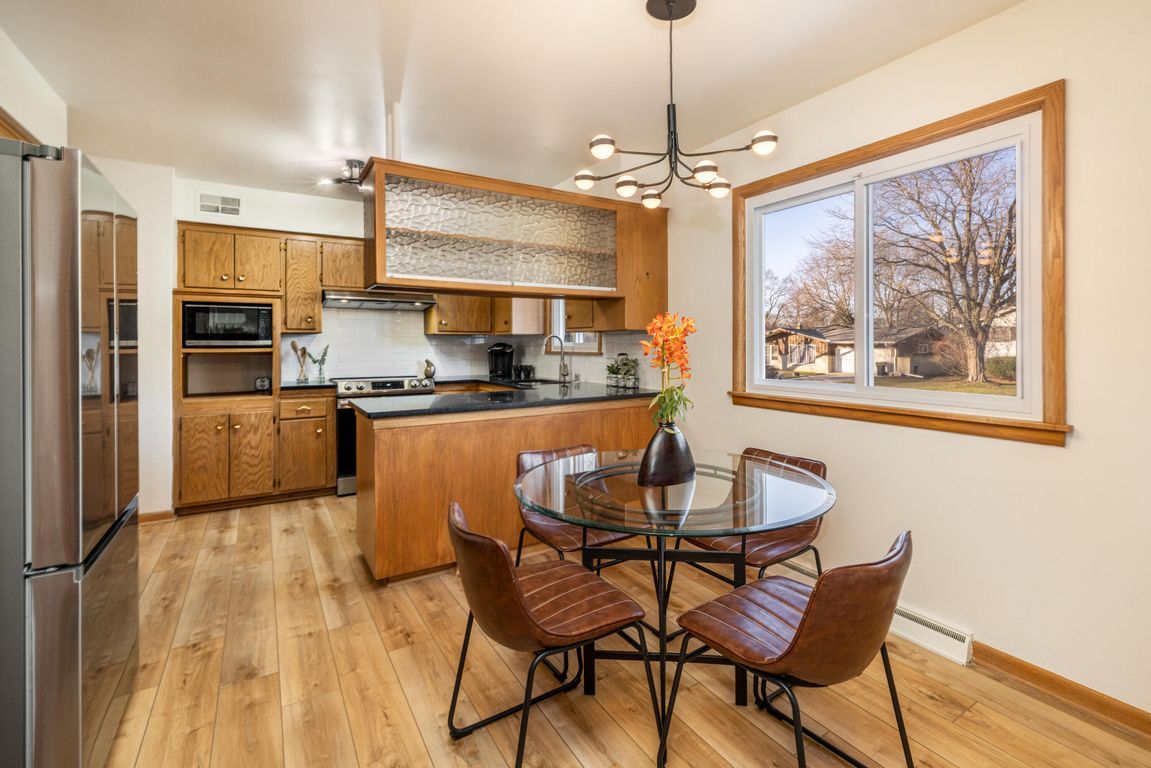A kitchen with a dining table and chairs and a large window.
