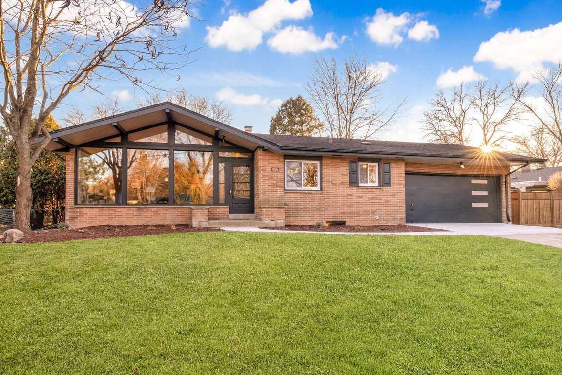 A brick house with a large lawn in front of it.