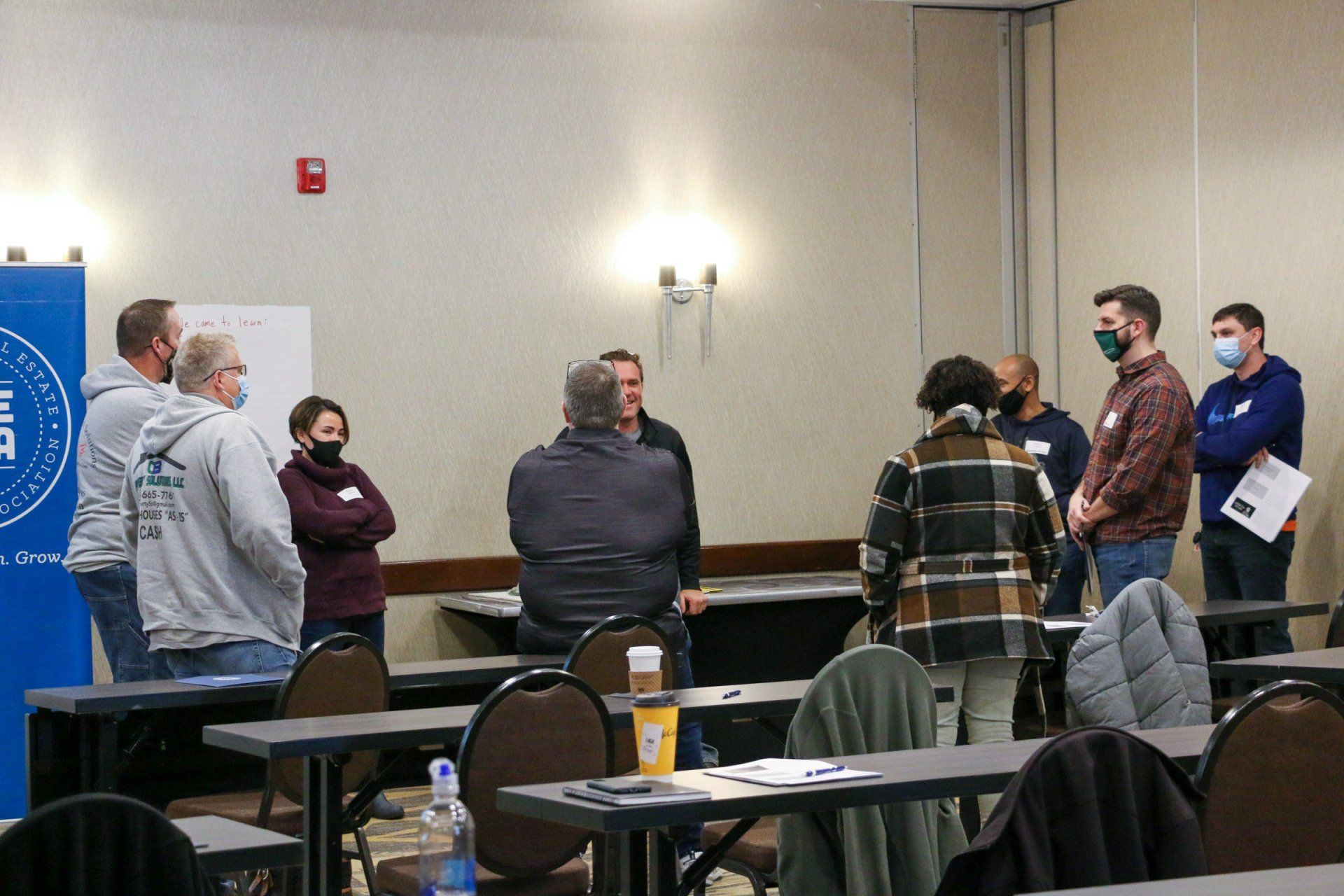 A group of people are standing around tables in a room.