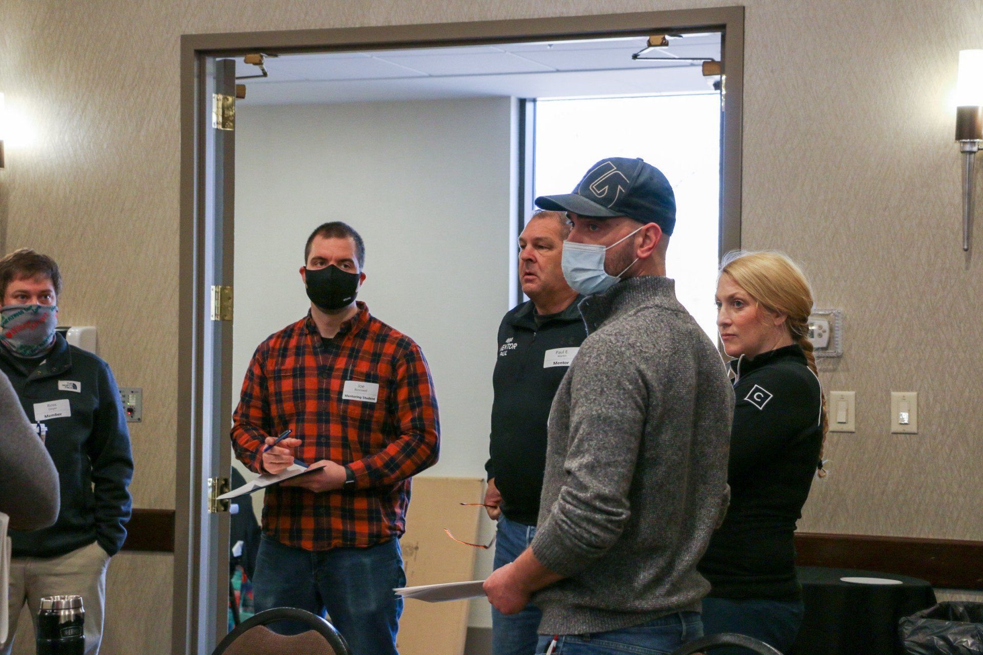 A group of people wearing face masks are standing in a room.