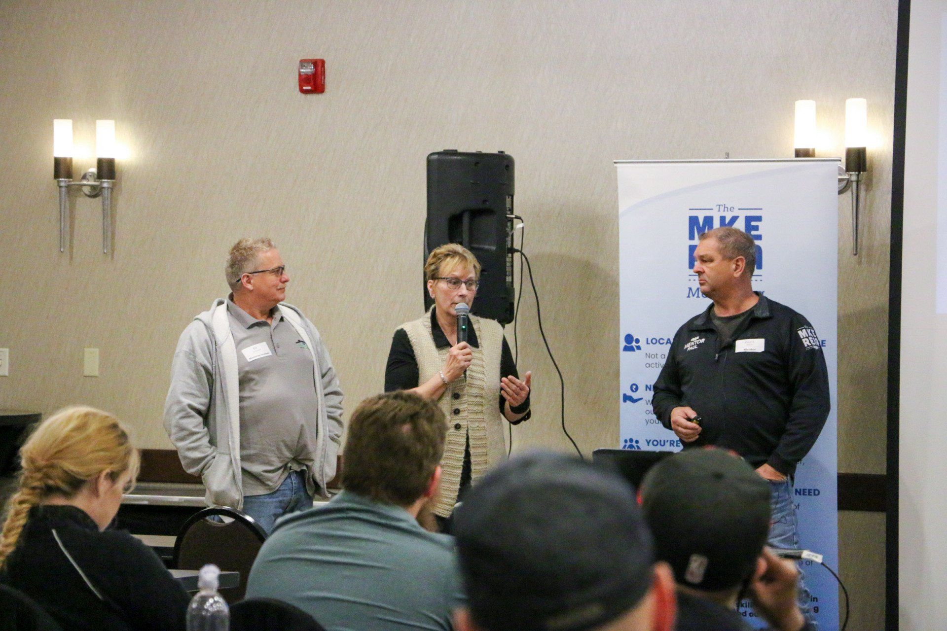A woman is speaking into a microphone in front of a group of people.