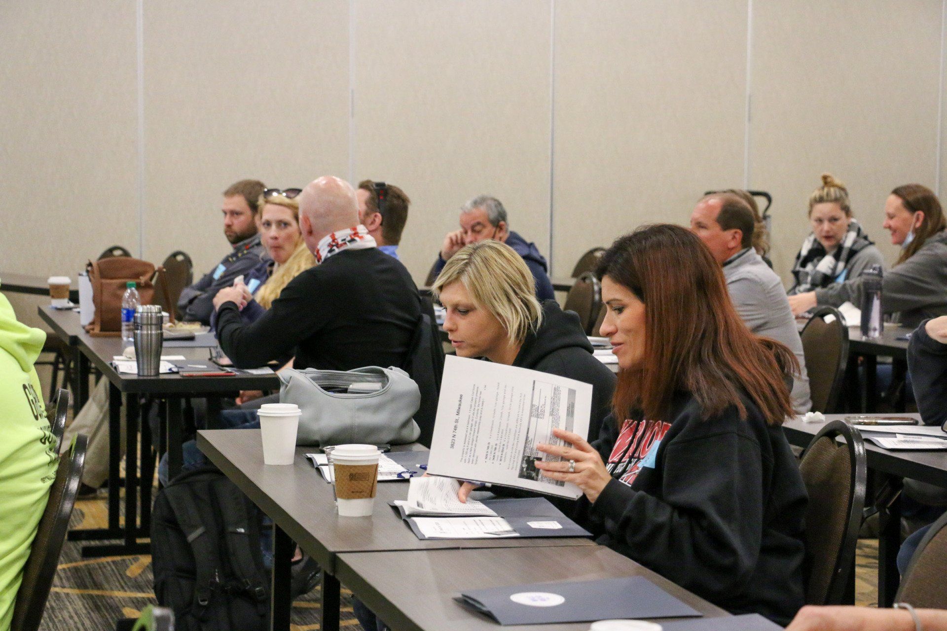 A group of people are sitting at tables in a conference room.