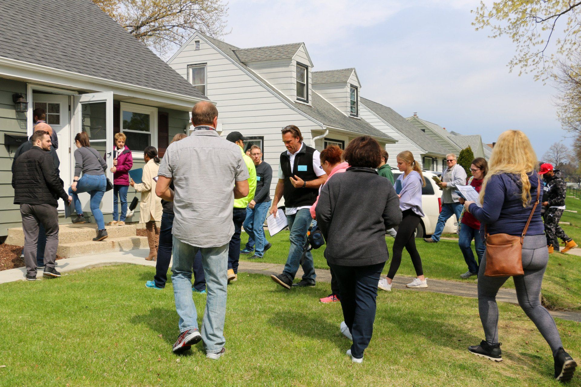 A group of people are walking in front of a house.