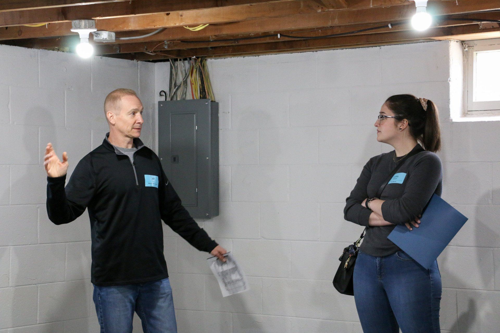 A man and a woman are standing in a basement talking to each other.