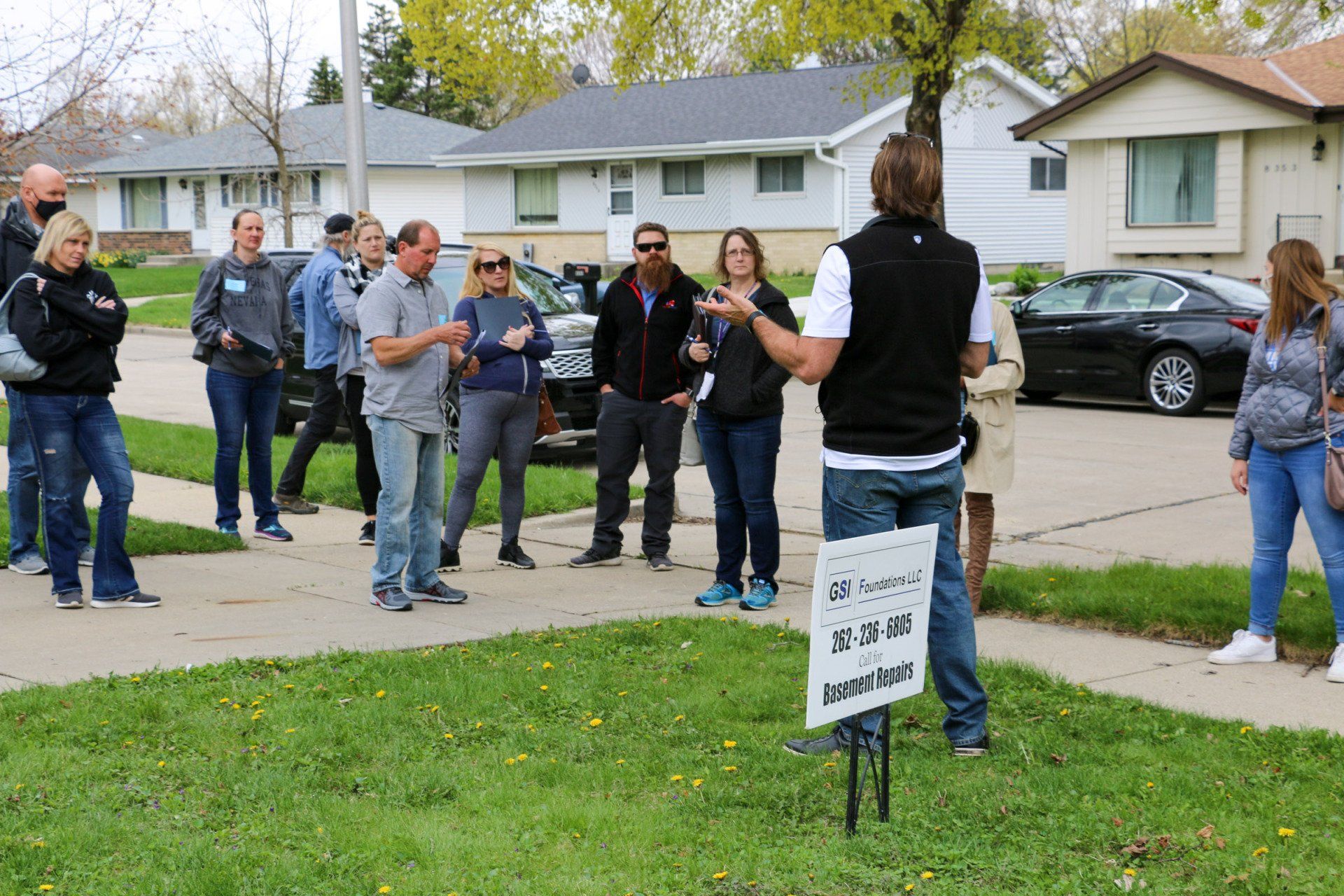 A man is standing in front of a group of people holding a sign that says for sale.