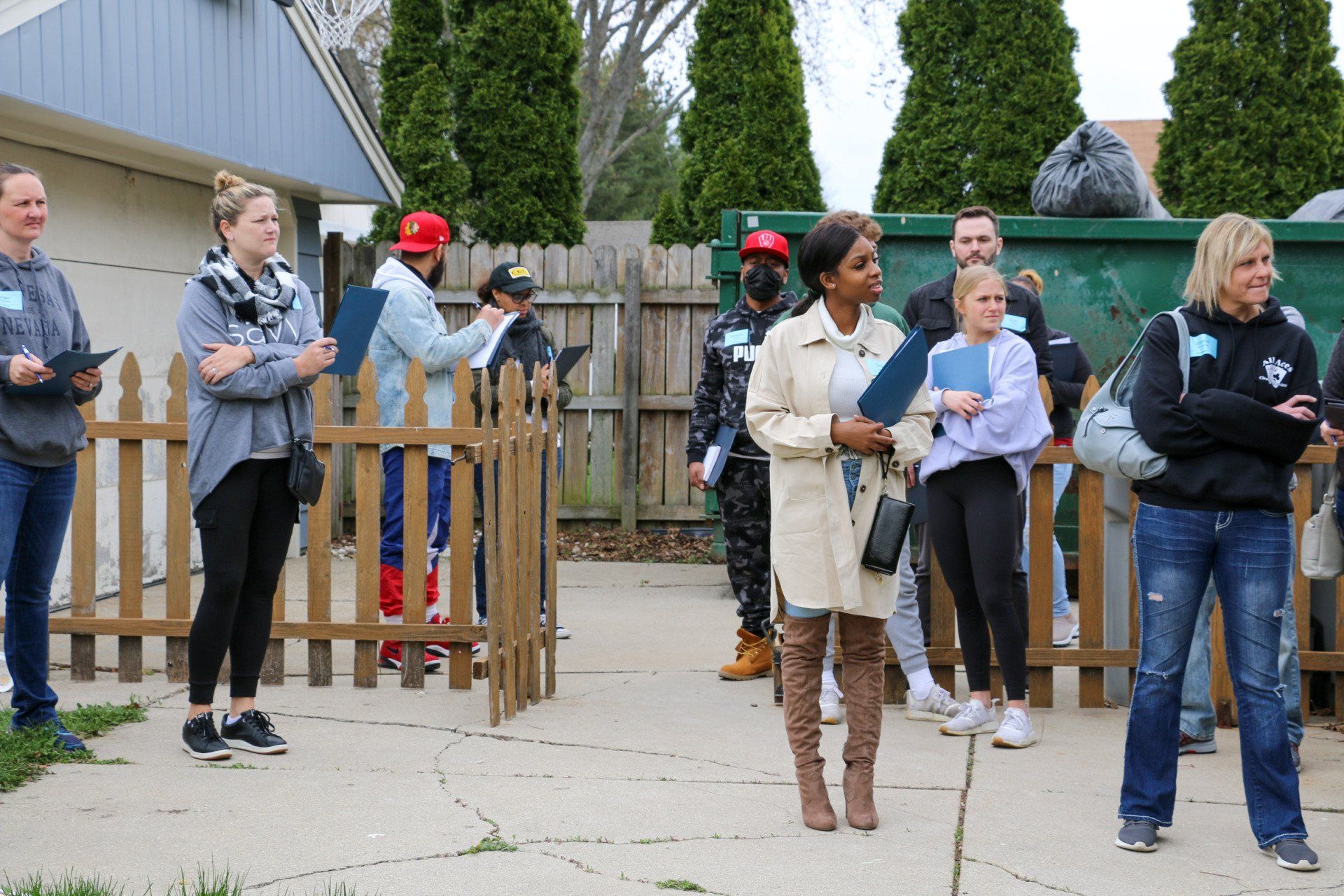 A group of people are standing in front of a wooden fence.
