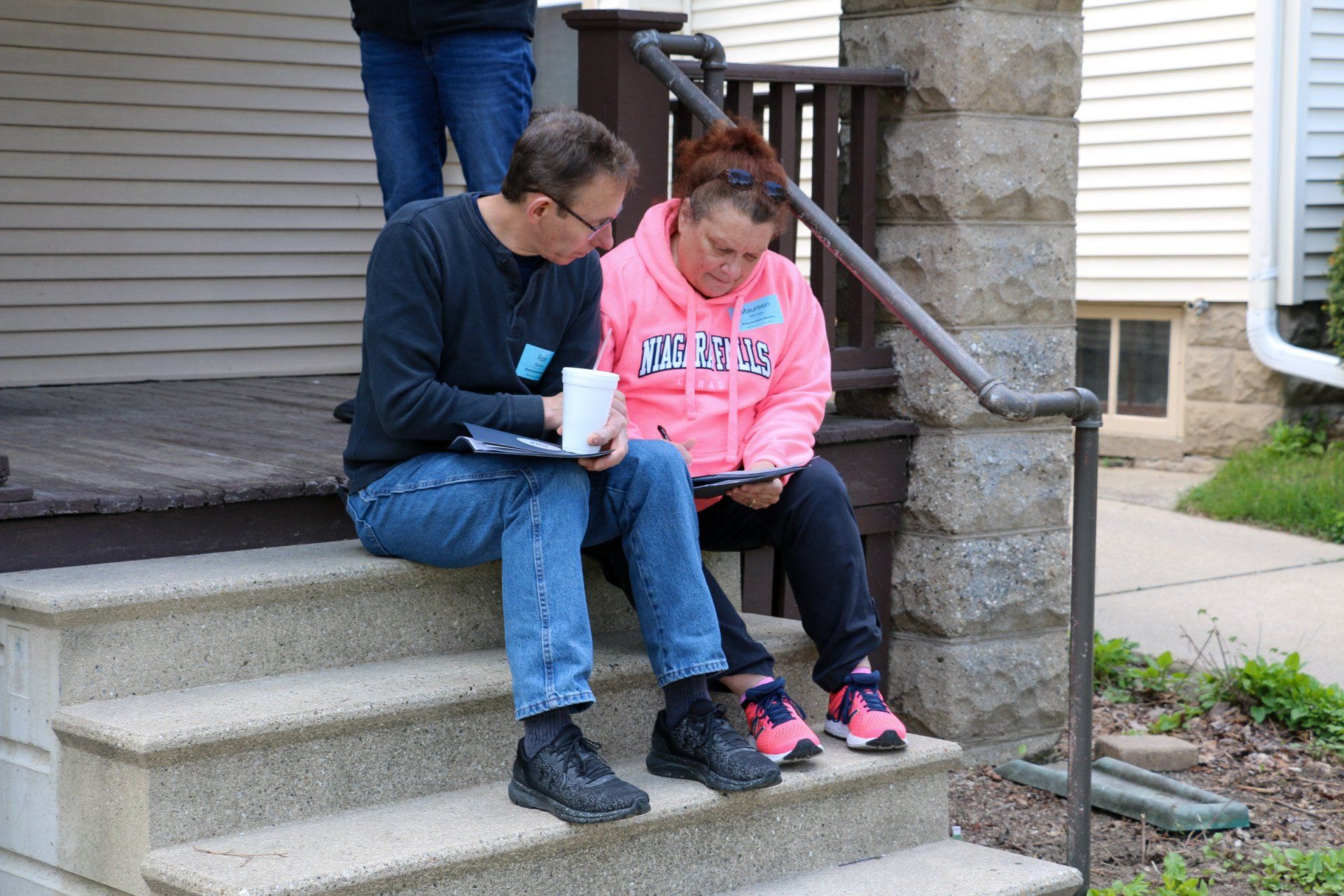 A man and a woman are sitting on the steps of a house.