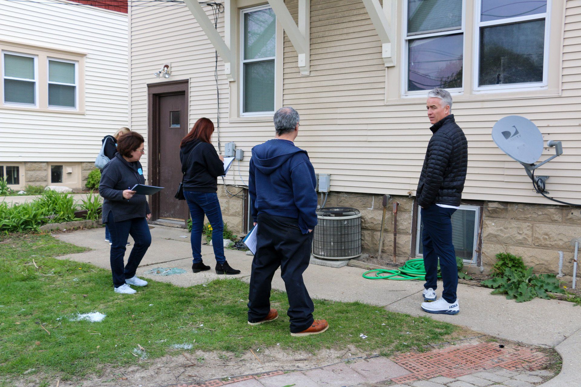 A group of people are standing in front of a house.