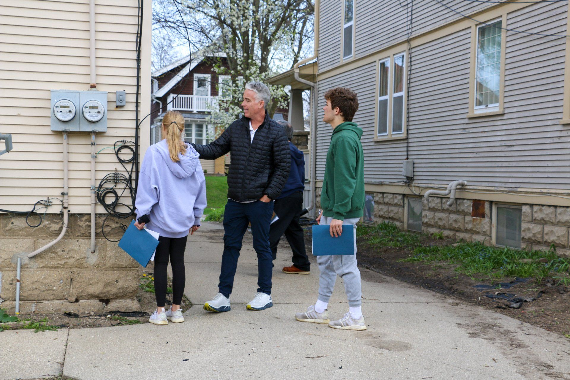 A group of people are standing on a sidewalk in front of a building.