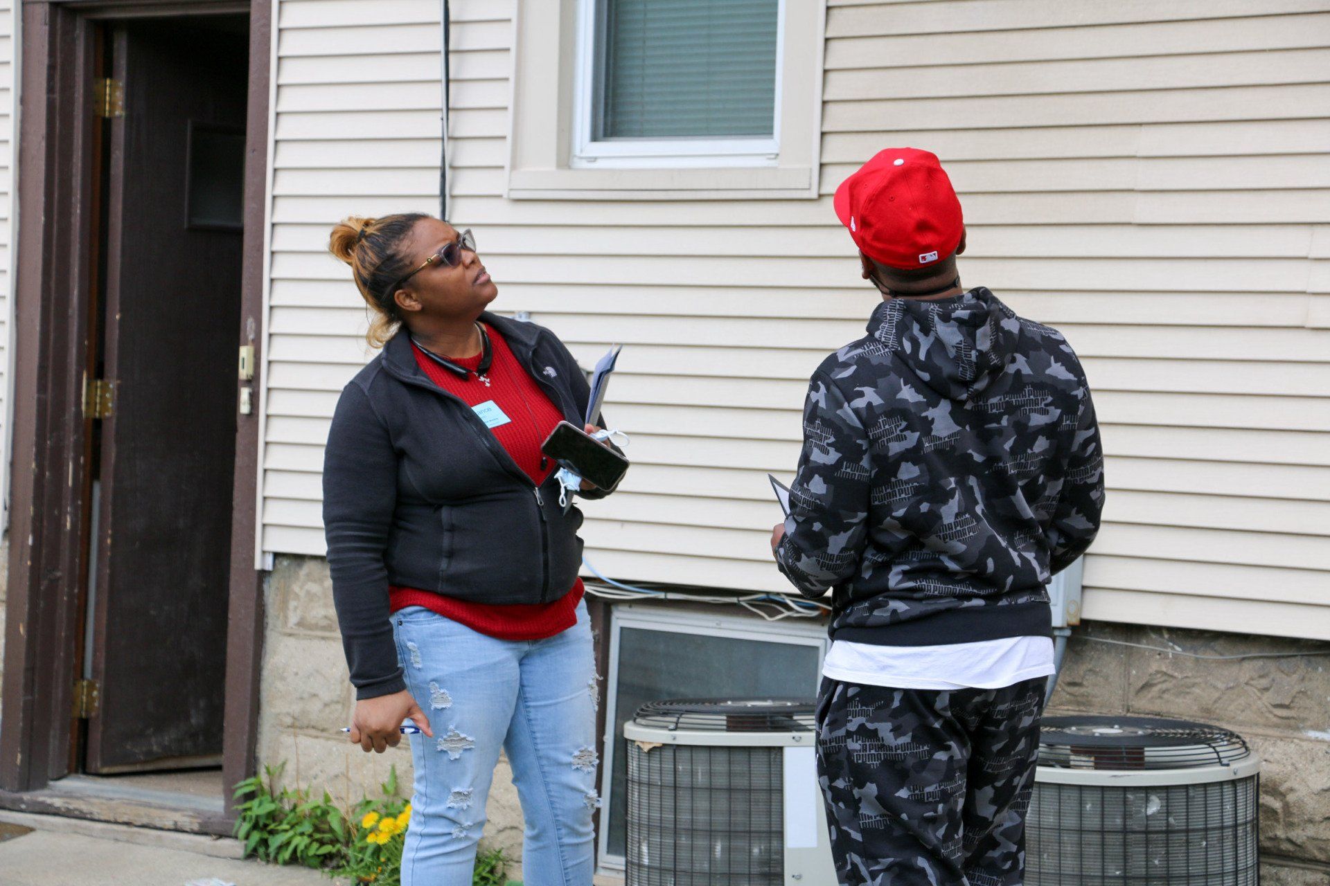 A woman is talking to a man in front of a house.