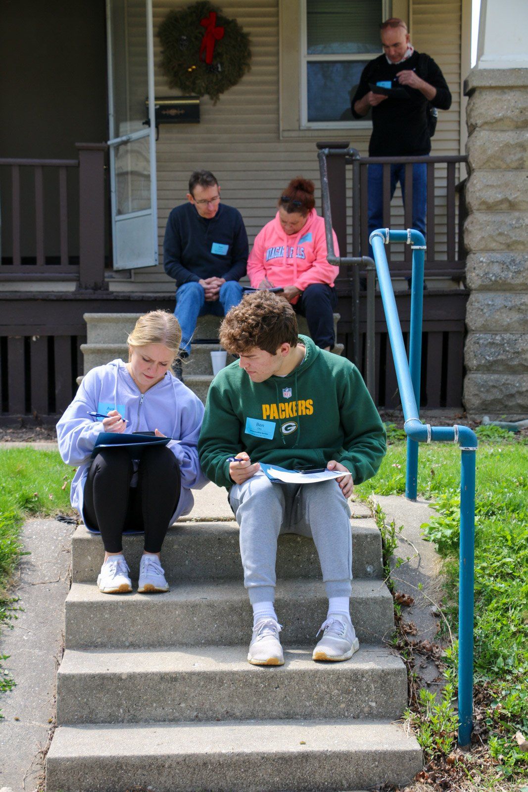 A group of people are sitting on the steps of a house.