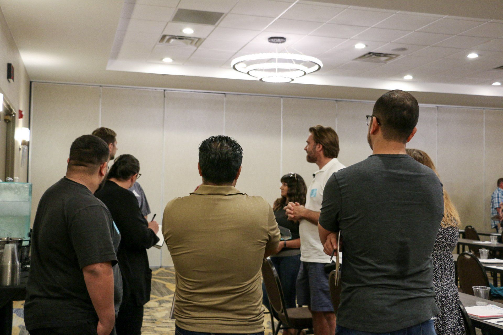 A group of people are standing in a room talking to each other.