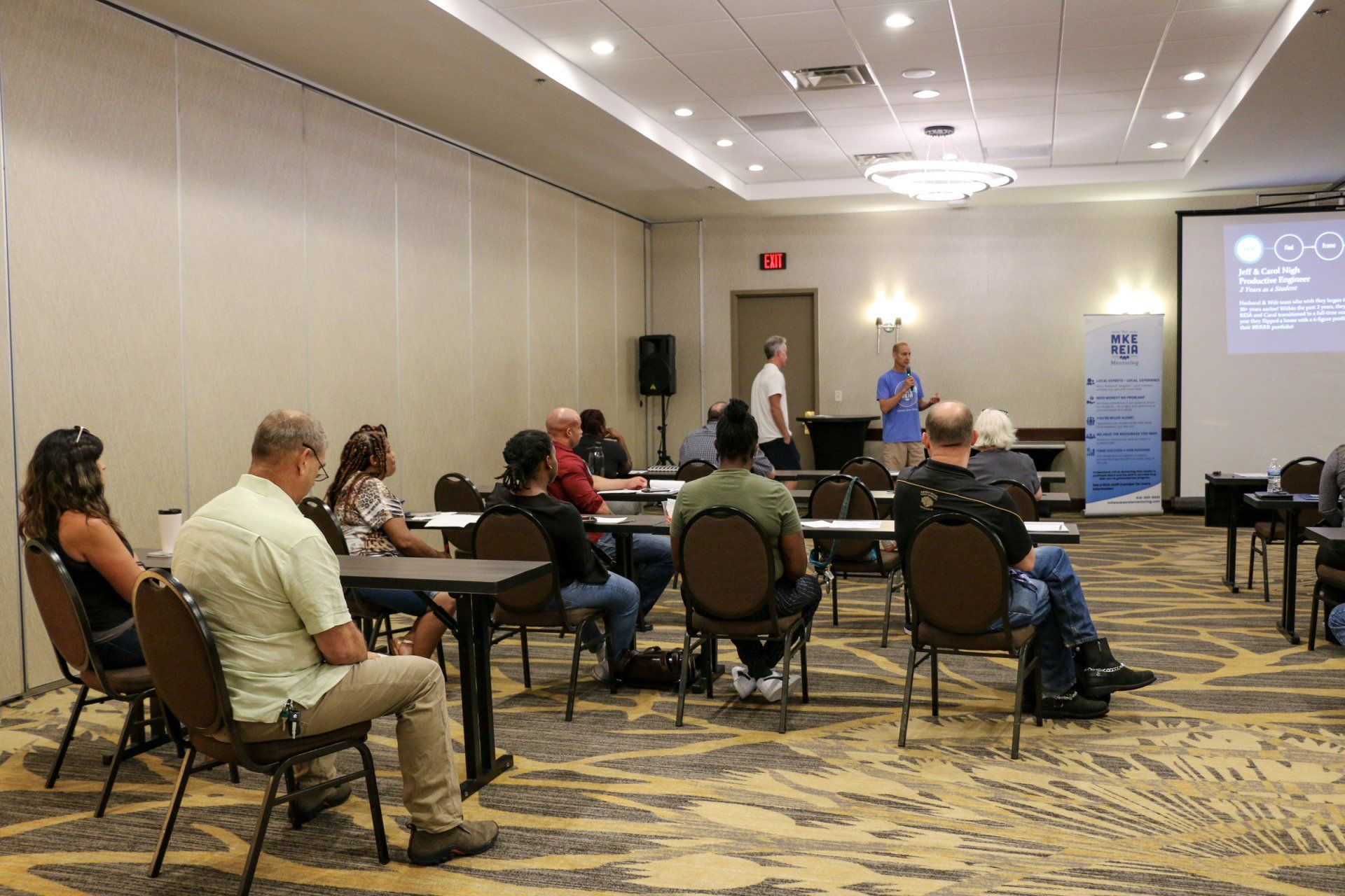 A group of people are sitting at tables in a conference room.