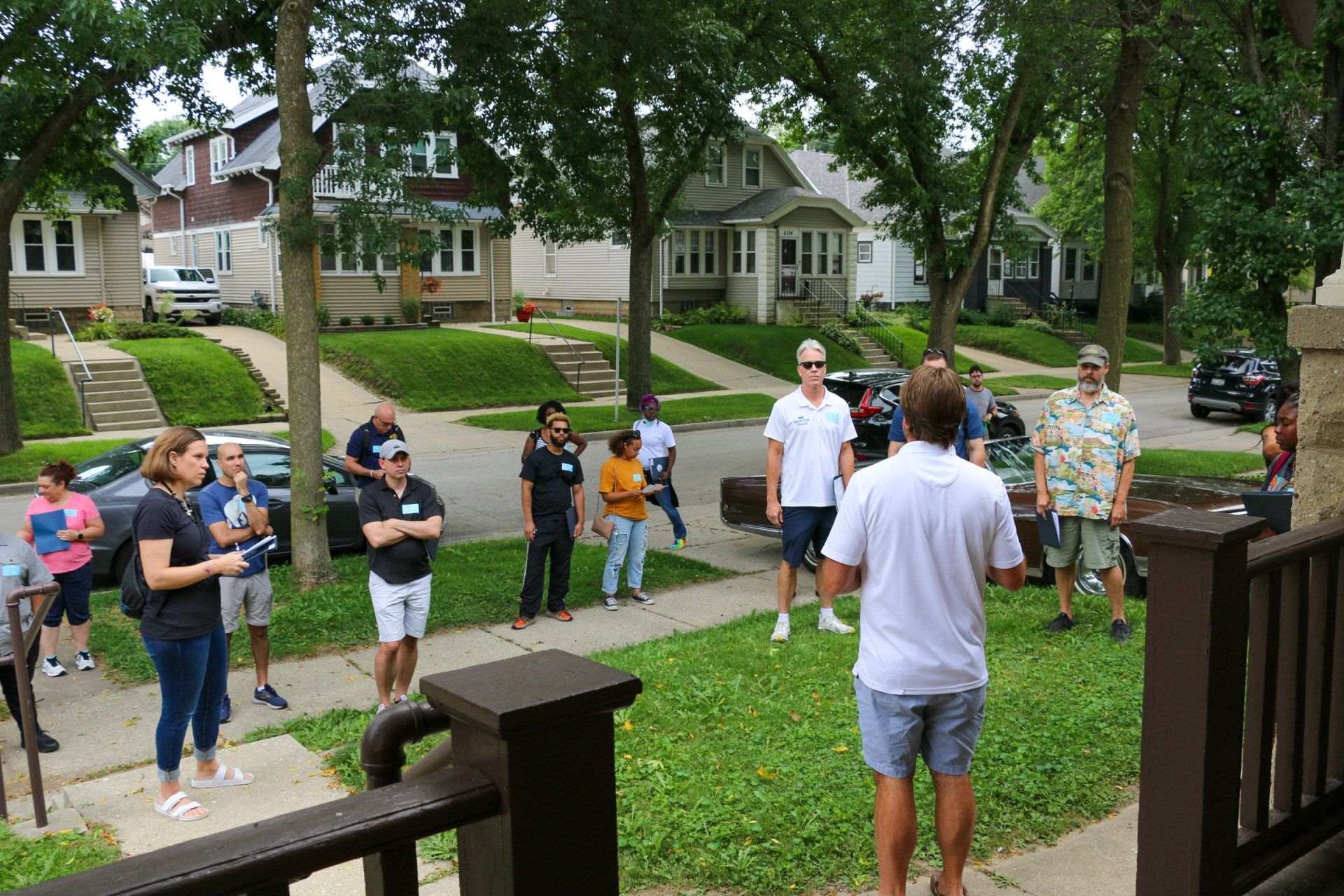 A man in a white shirt is standing in front of a group of people.
