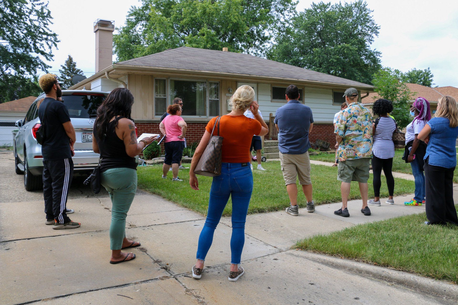 A group of people are standing in front of a house.