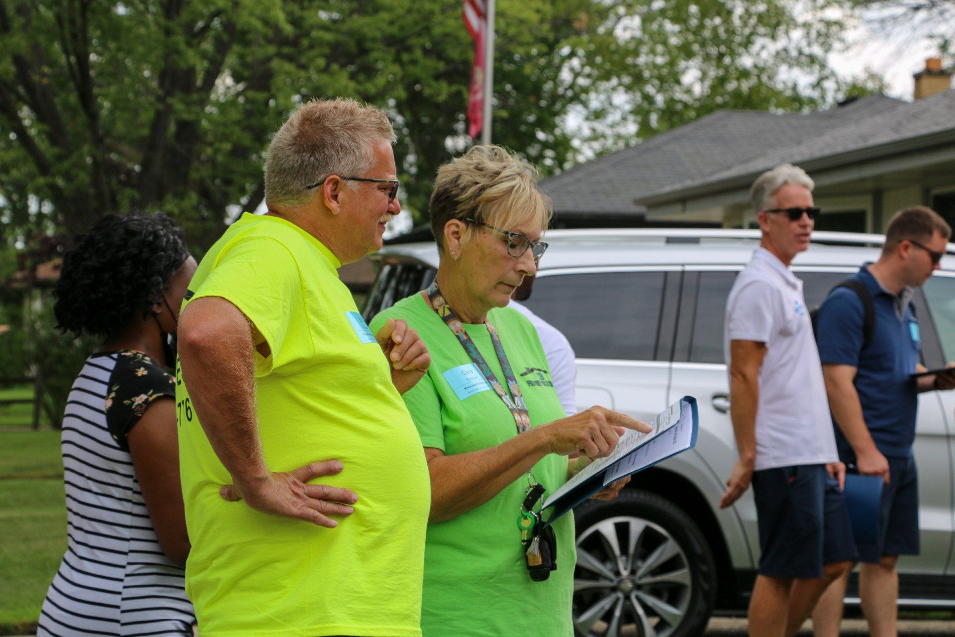A group of people are standing in front of a car.